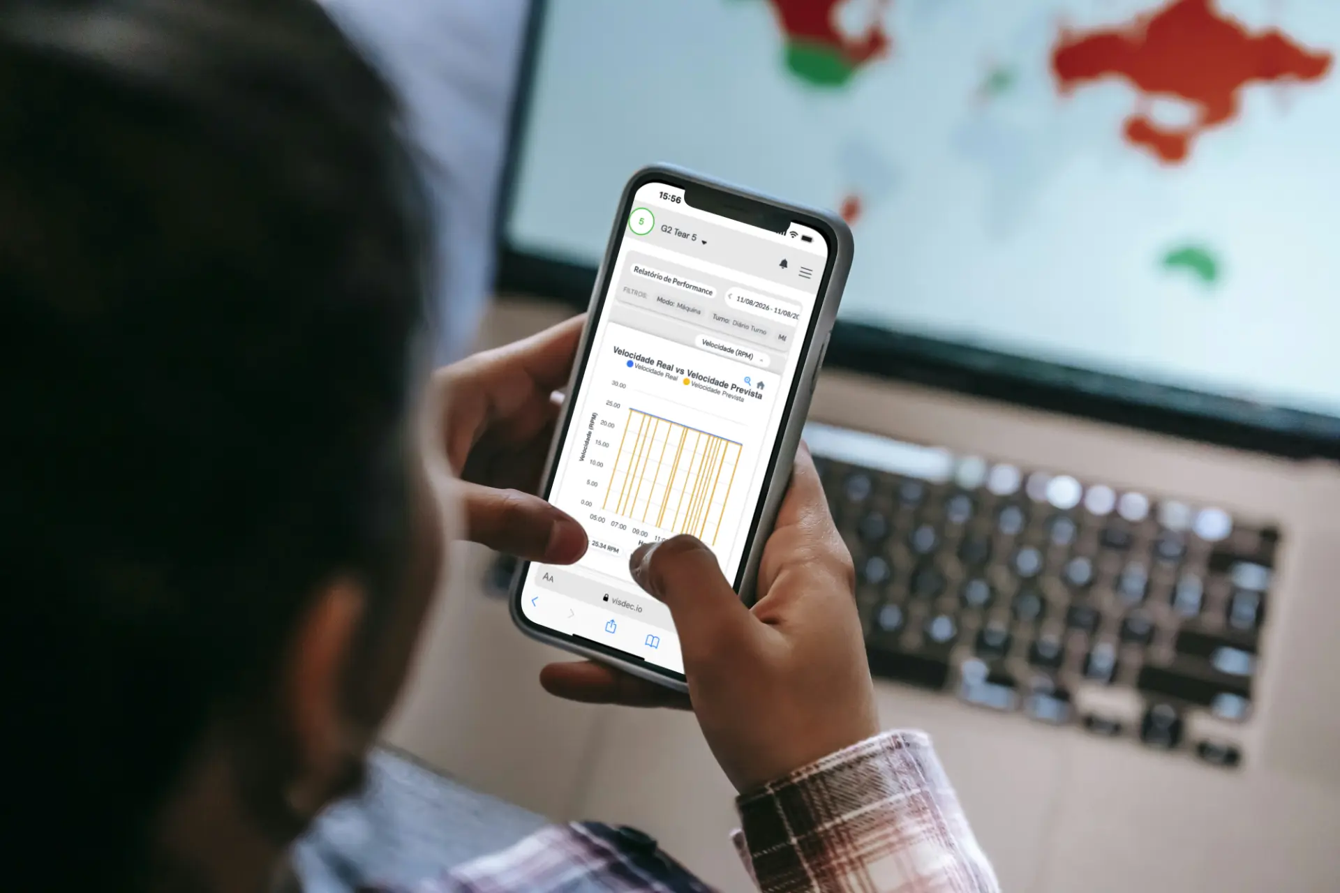 Operador acessando relatório de performance no celular com dashboard Visdec ao fundo
