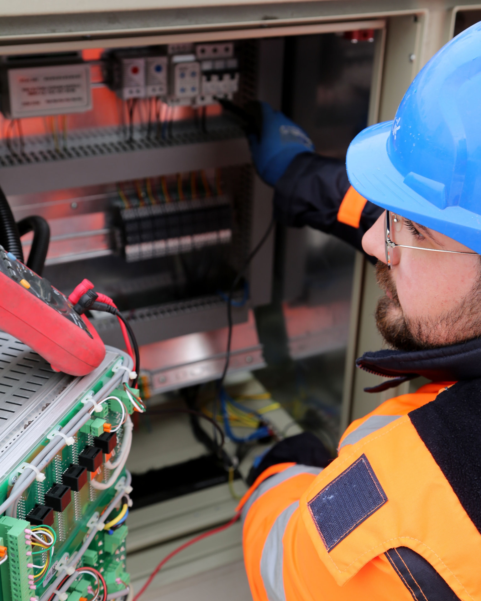 Técnico instalando medidores e sensores de telemetria em painel elétrico industrial