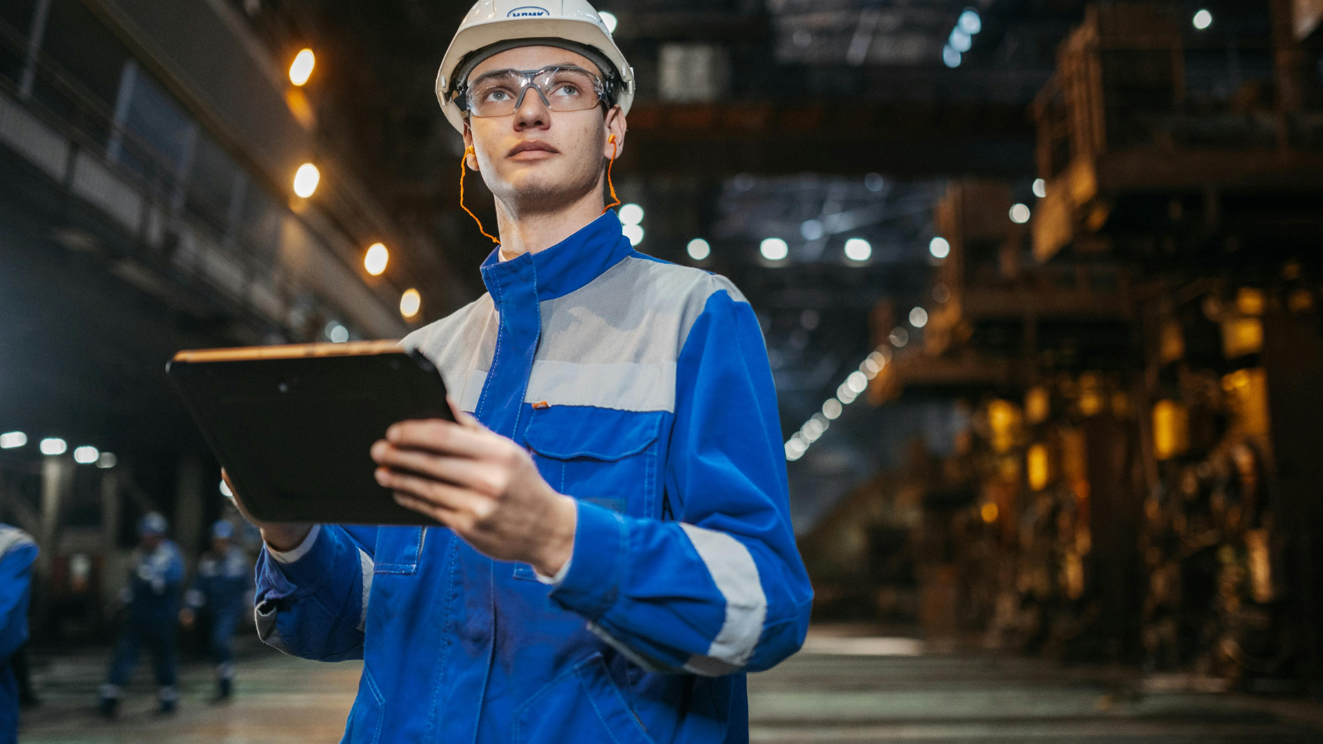 Operador industrial com tablet em chão de fábrica